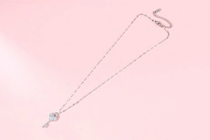 Detailed view of a rose gold key pendant necklace with clover pattern and micro-inlaid stones