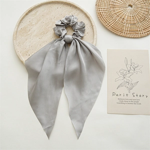 Detail of grey satin bow scrunchie with long ribbons on a decorative stone tray