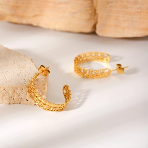 Close-up of gold hollow geometric C-shaped earrings with intricate textured details