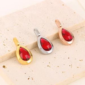 Detailed view of teardrop pendants in gold, silver, and rose gold with red ruby stones