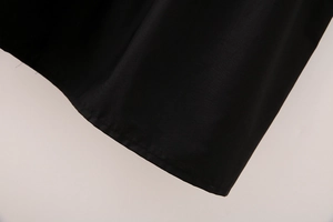 Détail de l'ourlet à couture plate sur cette robe midi noire en coton avec col en V