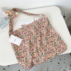 Detail of floral corduroy tote bag with wide strap on a minimalist white table