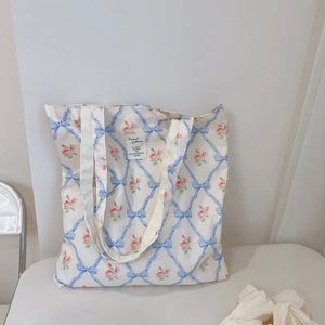 Close-up of floral canvas tote bag featuring blue ribbon bows and pink rose pattern