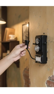 Close-up of vintage wall-mounted rotary telephone model with hand on handset on brick wall