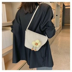 Detalle de bolso tipo cubo trenzado con flor amarilla y correa fina para el hombro chic