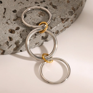 Detail of interlocking gold and silver rings displayed on a gray textured volcanic stone