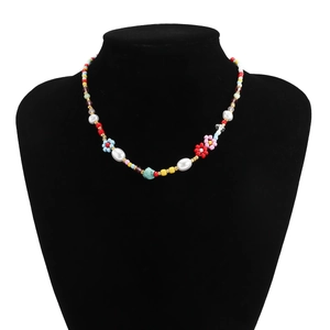 Detail view of colorful bohemian beaded necklace with daisy floral charms on a black mannequin