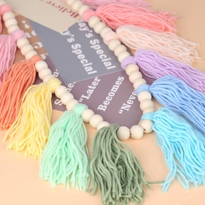 Detailed close-up of colorful cotton tassels and natural wood beads wall garland decoration