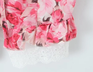 Close-up of pink floral fabric with ruffle trim and delicate white lace hem detail