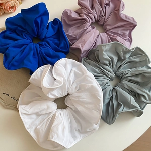 Gros plan de chouchous géants en tissu de couleurs bleu, violet, blanc et vert-gris