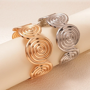 Artistic gold and silver spiral cuff bracelets with textured metallic circular patterns