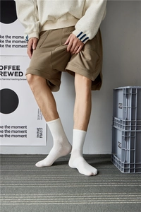 Detail of white cotton crew socks with vertical ribbing design on a lifestyle model