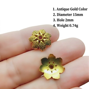 Detailed macro view of 15mm antique gold flower bead caps with engraved leaf textures