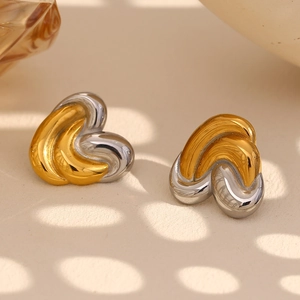 Macro detail of two-tone gold and silver twisted heart stud earrings with elegant shadows
