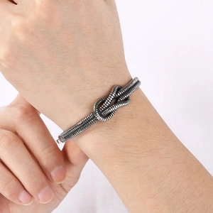 Close-up of a silver metal knot bracelet with a retro twisted design on a person wrist