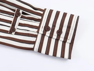 Detailed close-up of striped shirt cuff featuring coffee buttons and fine stitching