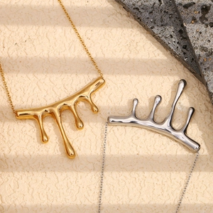 Detail of gold and silver liquid metal teardrop pendants on a natural stone background