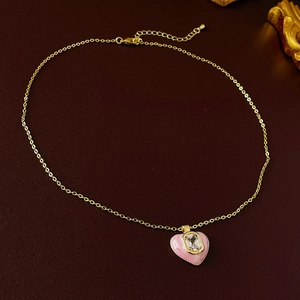 Detail of pink heart pendant with zircon on a golden chain shown on leather background