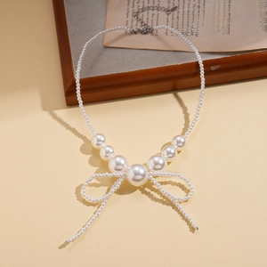 Detailed view of faux pearl necklace with bow pendant and silver lobster clasp closure