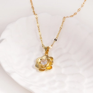 Detailed close-up of a golden rose pendant with a crystal center on a white shell tray
