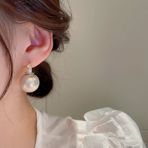 Boucles d'oreilles baroques avec perle et zircon dorées portées pour un look élégant