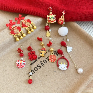 Detailed close-up of festive red enamel dancing lion earrings with soft white pom-poms