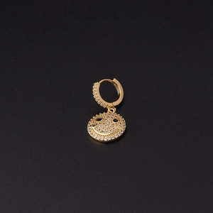 Detail of gold ear cuff with zircon smiley face charm on a black background