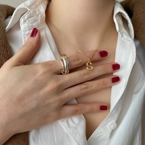 Golden letter S pendant necklace and multi-layer rings worn with elegant workwear