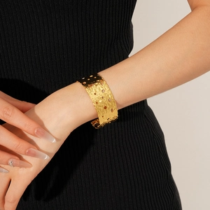Detail of wide hammered gold cuff bracelet with hollow circles on model wrist