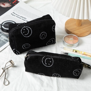 Detail of black corduroy makeup bag set with white smiley face and metal zipper