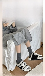 Detail of cozy black and white plush faux shearling slippers with double buckle straps