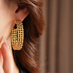 Close-up of a model wearing gold wide hollow chain-style C-shaped hoop earrings