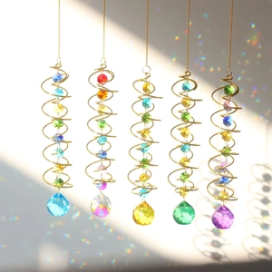 Rainbow reflections from crystal ball pendants hanging on golden metal spiral wind spinners
