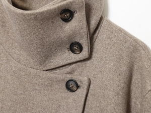 Détail d'une veste en laine camel montrant le col montant et des boutons texturés foncés