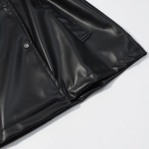 Gros plan détaillé sur la texture en similicuir noir avec bouton pression métallique