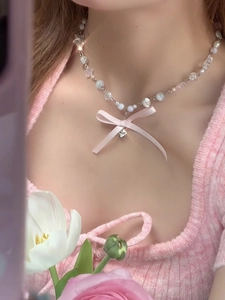 Détail de perles artificielles et perles de cristal avec un ruban rose sur le collier