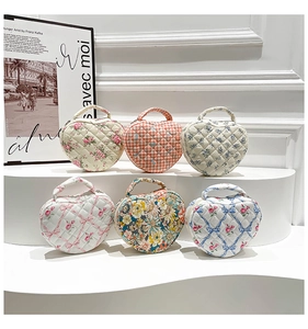 Multiple quilted floral cotton cosmetic bags with heart patterns and top handles on a stand