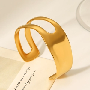 Detail of 18K gold-plated asymmetrical cutout bangle with a matte brushed metal texture