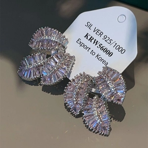 Detailed close-up of 925 sterling silver leaf earrings with sparkling pink gemstones