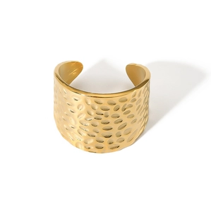 Macro view of wide gold open ring featuring unique hand-hammered metal texture