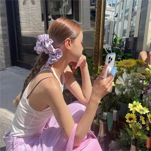 Photo en extérieur d'un chouchou en satin lilas porté sur un chignon élégant
