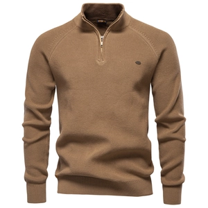 Close-up of camel knit sweater featuring a half-zip neckline and metallic logo detail