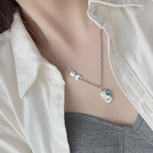 Silver necklace with blue zircon lucky pendant on beaded chain worn on white shirt