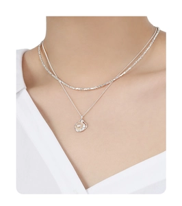 Detail of a double-layered S925 sterling silver necklace featuring a lustrous pearl pendant