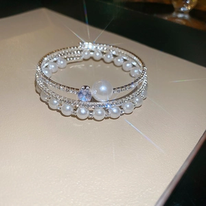 Close-up of silver layered bangle featuring brilliant zircons and elegant white pearls