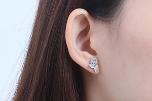 Detailed view of a silver rose flower stud earring on model with a metallic finish