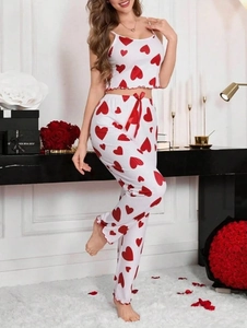 Detail of white ribbed pajamas with red hearts featuring ruffled hem and satin bow