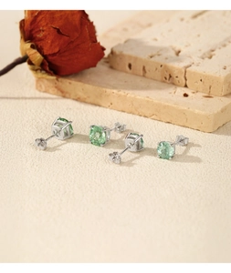 Close-up of S925 sterling silver earrings with round green gemstones and dry rose decor