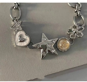 Detail of silver chain bracelet with star and heart charms featuring rhinestones