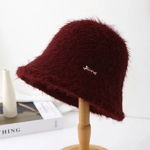 Gros plan sur un chapeau bob en peluche bordeaux avec logo métallique Paris doré sur support